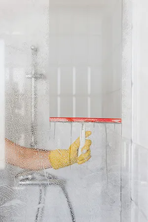 Bathroom cleaning service in Cincinnati: scrubbing a glass shower door